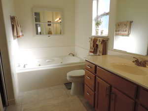 Primary bath with a tub with jets, vanity, and light tile patterned flooring