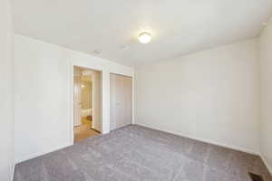 Unfurnished bedroom featuring a textured ceiling, carpet floors, a closet, and connected bathroom