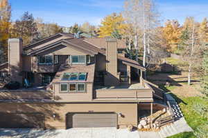Rear view of property with a chimney, a wooden deck, and an attached garage