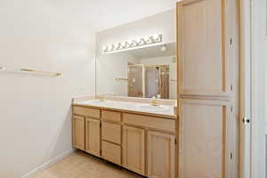Bathroom featuring double vanity, a shower stall, and light tile patterned floors