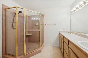 Bathroom featuring double vanity, light tile patterned flooring, and a shower stall
