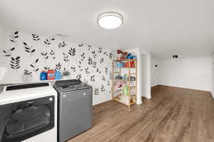 Washroom with wood finished floors, washing machine and dryer, and a textured ceiling