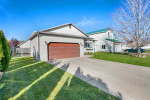 View of front of home with concrete driveway, an attached garage, and a gate