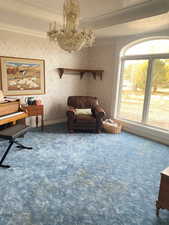 Living area featuring carpet flooring, a chandelier, wallpapered walls, and crown molding