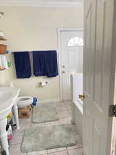 Full bath with a bathtub, ornamental molding, and light tile patterned floors