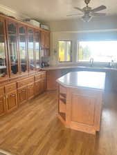 Kitchen with a textured ceiling, brown cabinets, glass insert cabinets, a kitchen island, and dark wood-type flooring