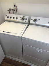 Washroom featuring dark wood-style flooring and washing machine and clothes dryer