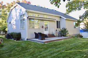 Rear view of property featuring a deck, stucco siding, and a shingled roof