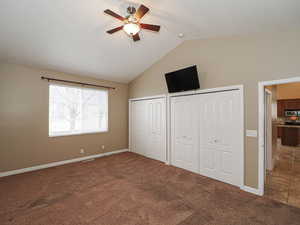Unfurnished bedroom featuring multiple closets, dark colored carpet, and ceiling fan