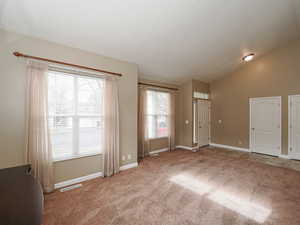 Unfurnished room featuring lofted ceiling and light colored carpet