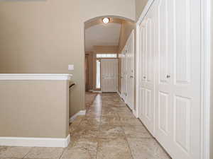 Hallway featuring arched walkways and light tile patterned floors