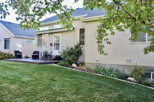 Rear view of property featuring a yard, stucco siding, and a wooden deck