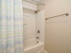 Full bath with shower / bath combination with curtain and baseboards