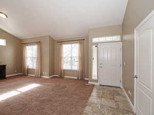 Entryway featuring healthy amount of natural light, light colored carpet, and vaulted ceiling
