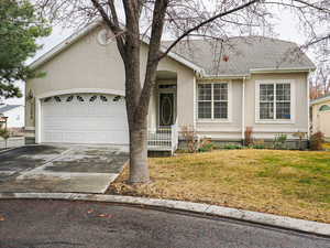 View of front of property with stucco siding, a front lawn, concrete driveway, an attached garage, and a shingled roof