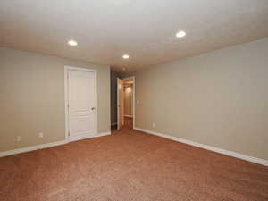 Carpeted empty room with baseboards and recessed lighting