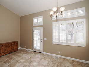 Foyer with suspended lighting, plenty of natural light, and lofted ceiling