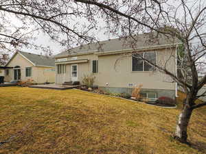 Rear view of house featuring a patio area, a lawn, and stucco siding