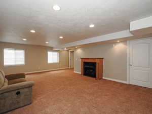 Basement with a fireplace, light carpet, recessed lighting, and a textured ceiling