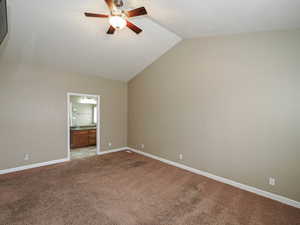 Unfurnished bedroom featuring ensuite bathroom, lofted ceiling, carpet floors, and ceiling fan