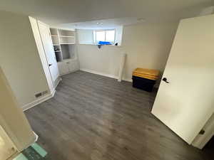 Below grade area featuring dark wood-style flooring and baseboards