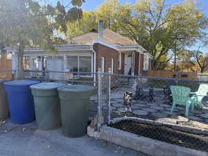 Back of property featuring a fenced front yard, a patio, brick siding, a sunroom, and a chimney