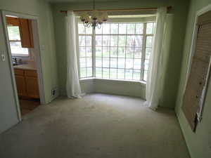 Unfurnished dining area featuring carpet flooring and a chandelier