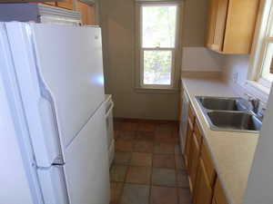 Kitchen with white appliances, light countertops, and light brown cabinetry