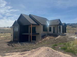 View of property exterior with a patio area, a shingled roof, and board and batten siding