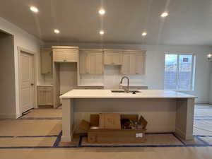 Kitchen with light stone countertops, recessed lighting, a center island with sink, and a textured ceiling