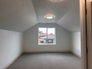 Additional living space featuring light carpet and baseboards