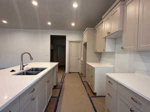 Kitchen with light stone counters, recessed lighting, and gray cabinetry