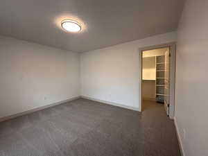 Spare room featuring dark carpet and baseboards