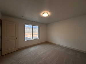 Empty room with light colored carpet and baseboards