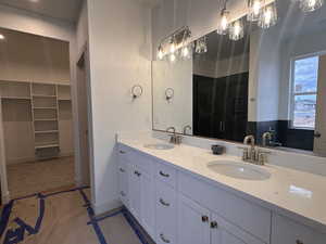 Bathroom with double vanity, a walk in closet, and a shower stall