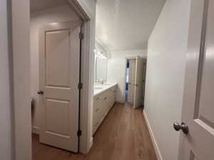 Bathroom with light wood-type flooring, double vanity, and a textured ceiling