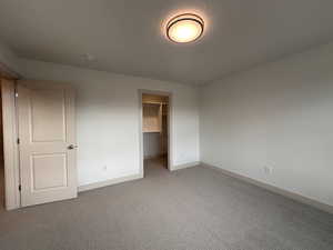 Unfurnished bedroom featuring a spacious closet and carpet floors