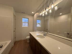 Full bath with vanity, dark wood-style flooring, and recessed lighting