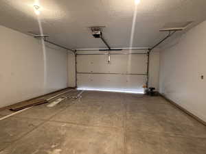Garage featuring baseboards and a garage door opener