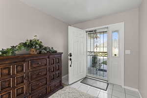 Foyer with light tile patterned flooring and baseboards