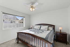 Carpeted bedroom with a ceiling fan and baseboards
