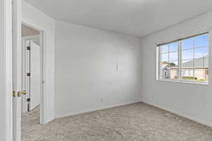 Unfurnished room featuring light carpet and baseboards