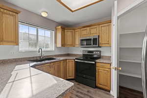 Kitchen featuring appliances with stainless steel finishes, dark wood finished floors, brown cabinets, and light countertops