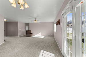 Unfurnished room featuring a chandelier, light carpet, and a ceiling fan