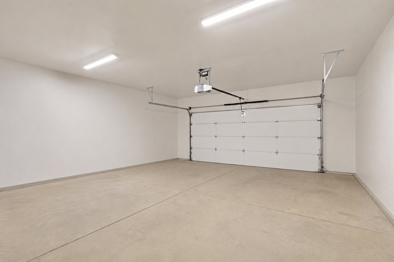 Spacious garage featuring a concrete floor, white walls, and bright overhead lighting
