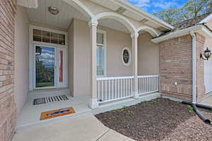 Property entrance featuring brick siding and covered porch