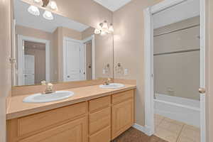 Full bathroom featuring light tile patterned floors, double vanity, and tub / shower combination