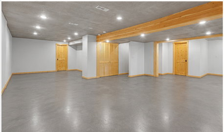 Expansive unfinished space featuring concrete flooring, exposed wood beams, recessed lighting, neutral painted walls, and natural wood doors