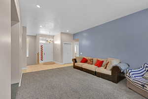 Living area featuring light carpet, a chandelier, light tile patterned floors, recessed lighting, and a textured ceiling