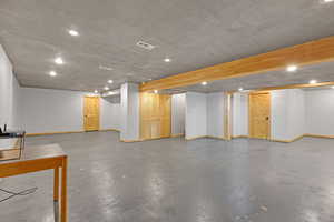 Finished basement with recessed lighting and a textured ceiling